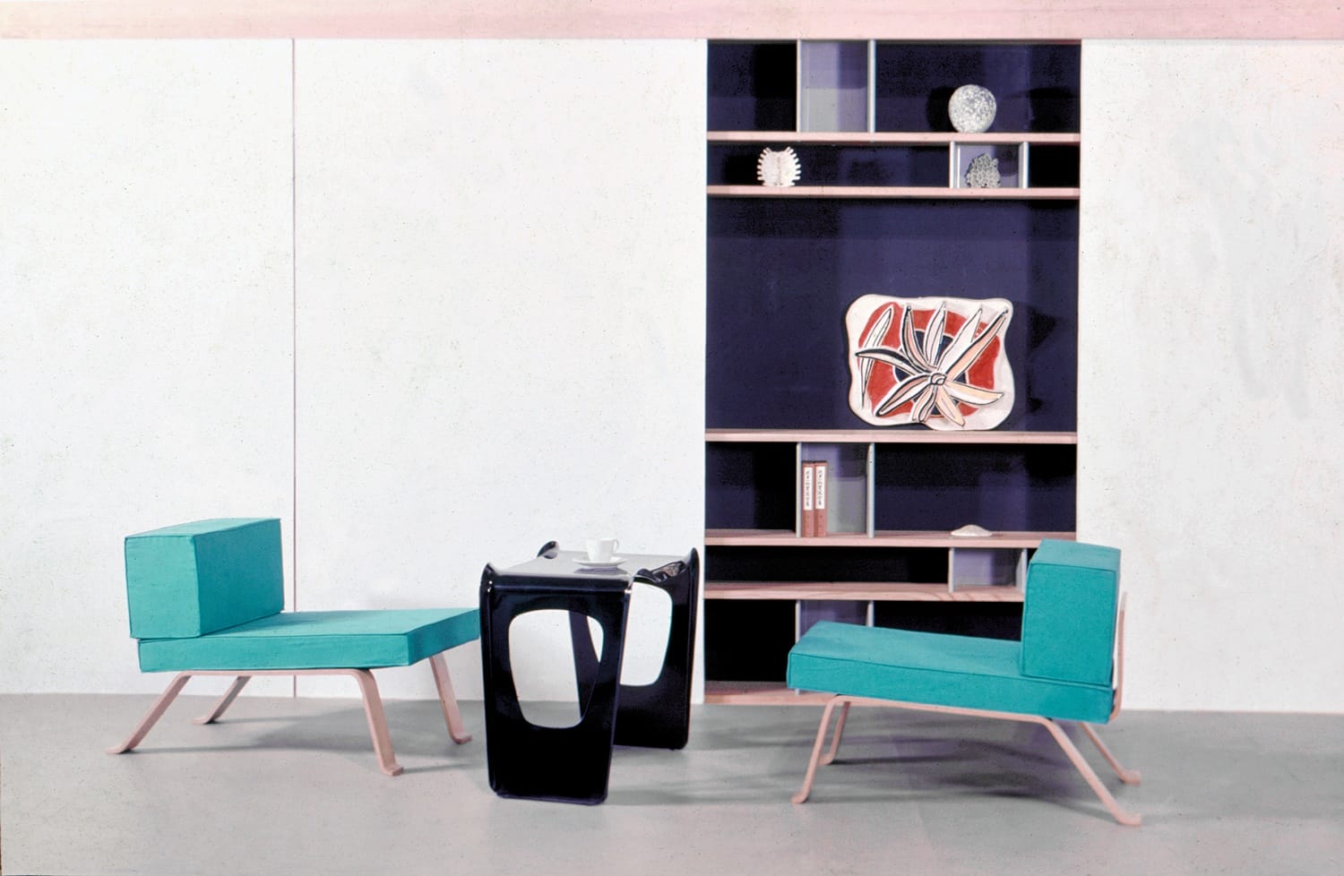 Modern living room with turquoise chairs, black coffee table, and abstract art on a dark bookshelf background.