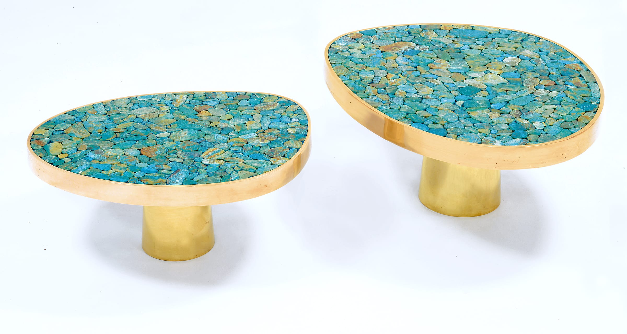 Two modern oval tables with turquoise stone tabletops and gold cylindrical bases.