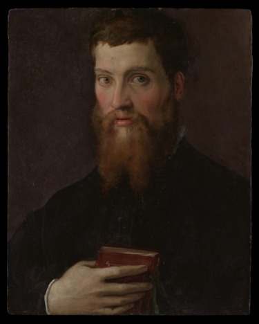 Portrait of a bearded man holding a book against a dark background, conveying a sense of seriousness and contemplation.
