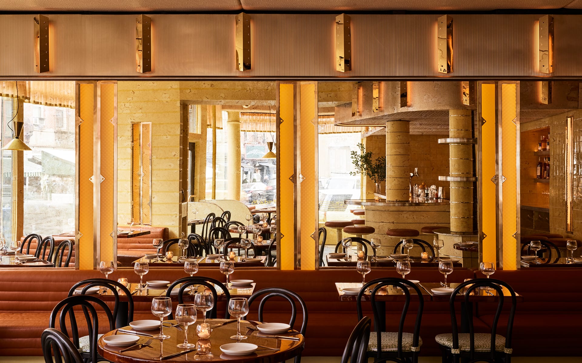 Cozy restaurant interior with elegant table settings, warm lighting, and a view of the bar area in the background.
