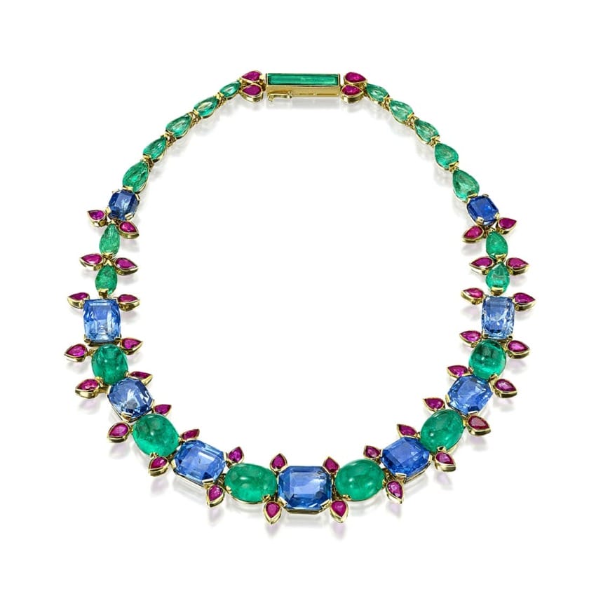 Colorful gemstone necklace with blue, green, and pink stones arranged in a symmetrical pattern on a white background.