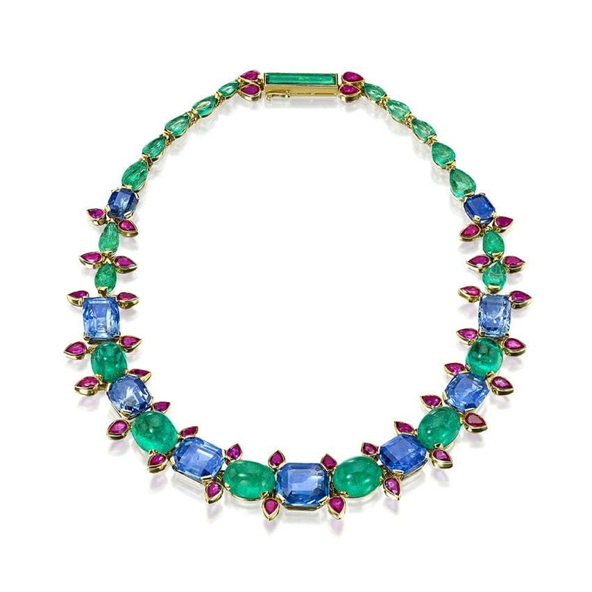 Colorful gemstone necklace with blue, green, and pink stones arranged in a symmetrical pattern on a white background.