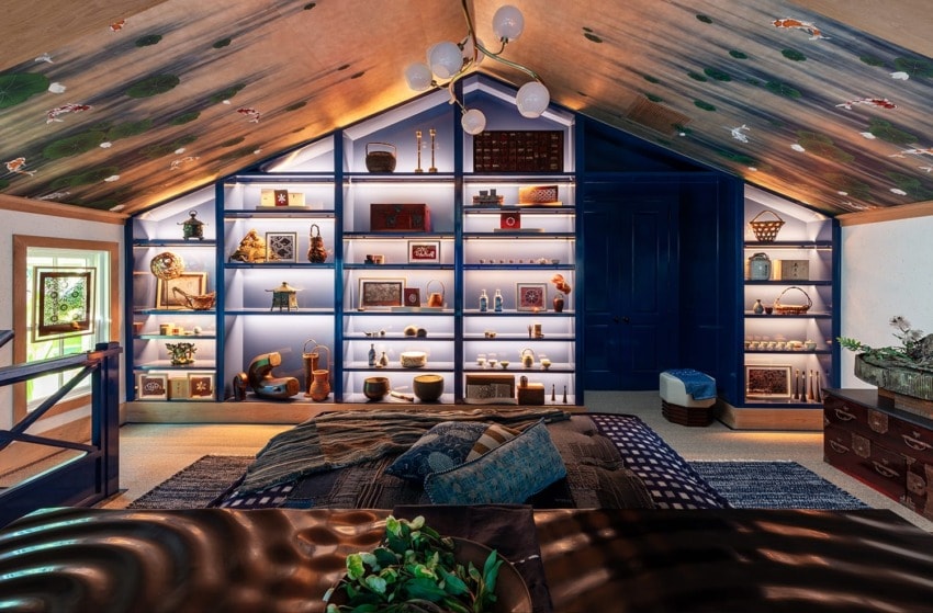 Cozy attic room with vibrant blue shelving displaying various eclectic decor, under a painted ceiling, ambient lighting.