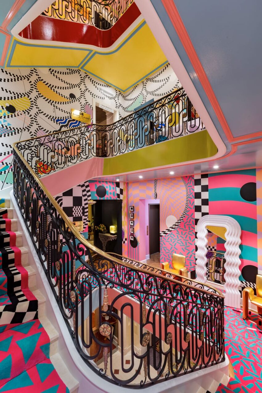 Colorful, eclectic interior with geometric patterns, bold colors, and ornate railing in a multi-level room.