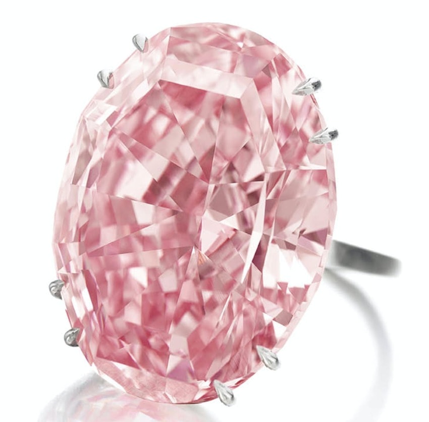 oval-shaped pink diamond ring with silver prongs against a white background