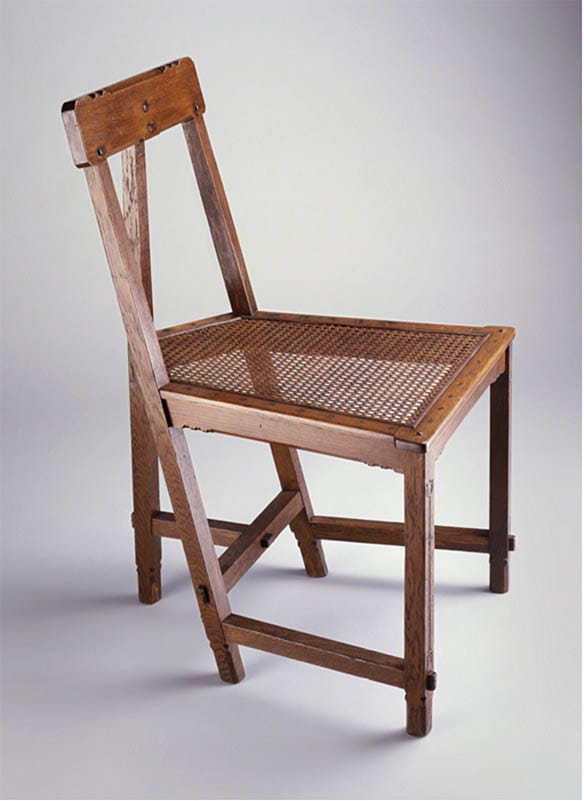 Wooden chair with woven cane seat and backrest, facing left, showing simple, rustic design against a plain background.