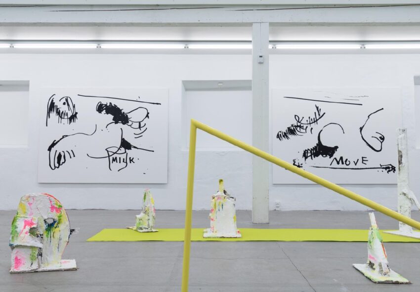 Contemporary art gallery with abstract black and white paintings and colorful sculptures on the floor