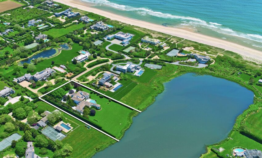 Aerial view of coastal homes surrounded by greenery, near a beach and a body of water.