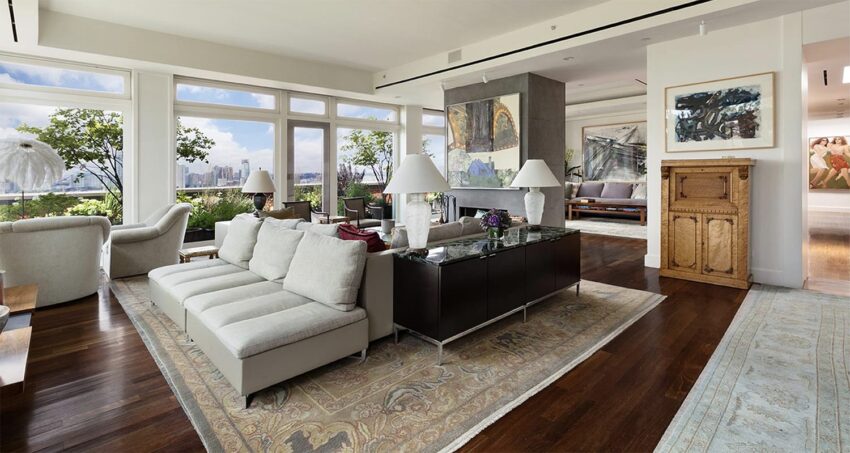 Luxurious living room with modern furniture, large windows, green plants, a decorative rug, and contemporary art on the walls.
