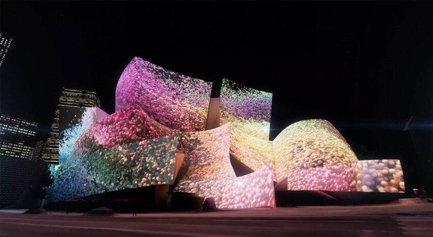 Colorful light projection on a modern, abstract architectural building at night, displaying vibrant pinks, purples, and yellows.