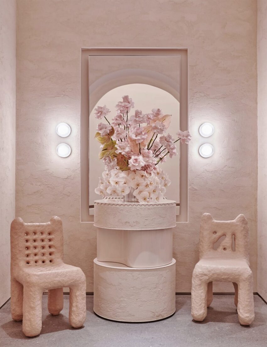 Elegant modern interior with two textured chairs, a decorative floral arrangement, and soft wall lighting.