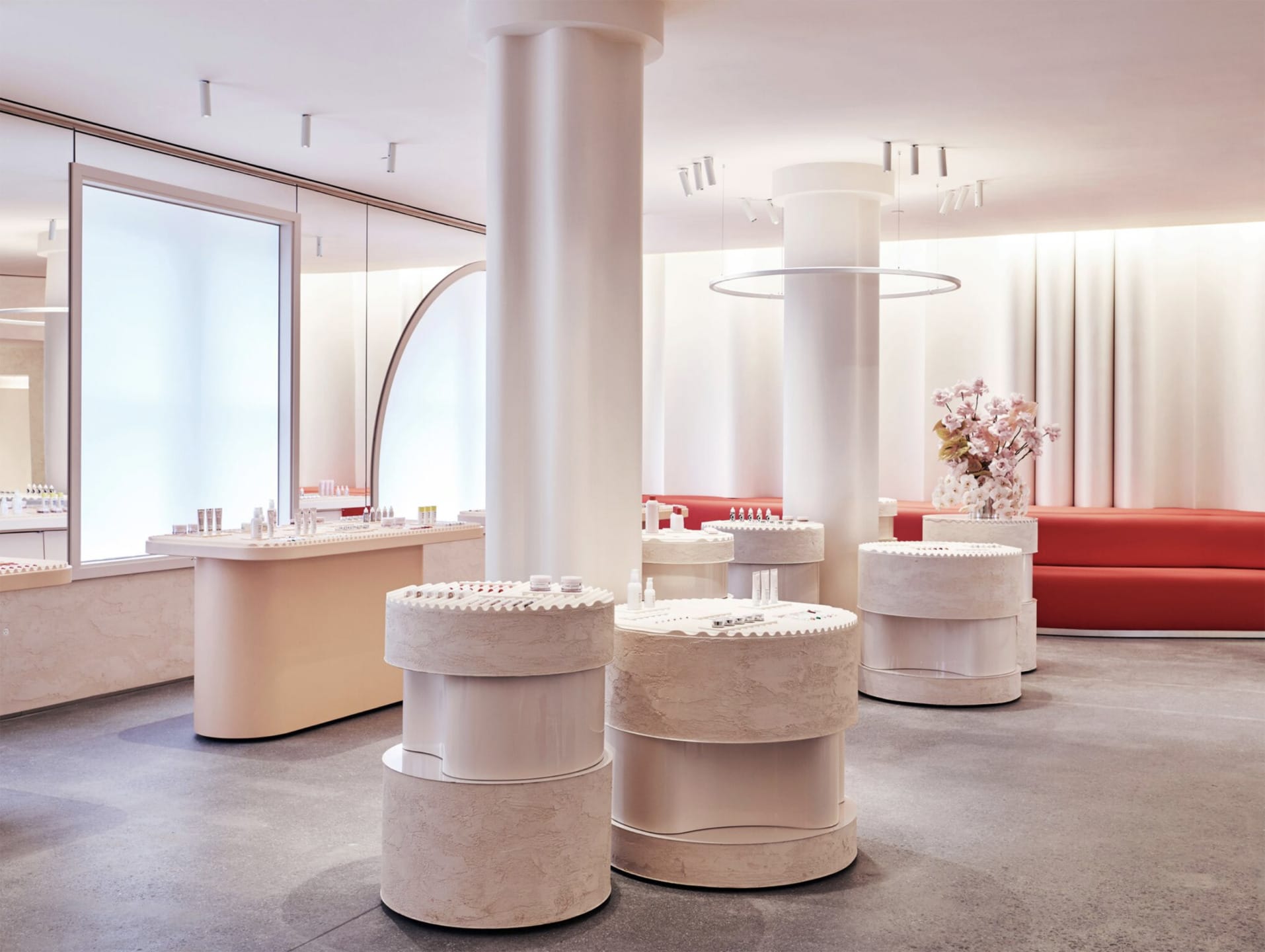 Elegant modern store interior with round display tables, red seating, and soft lighting.