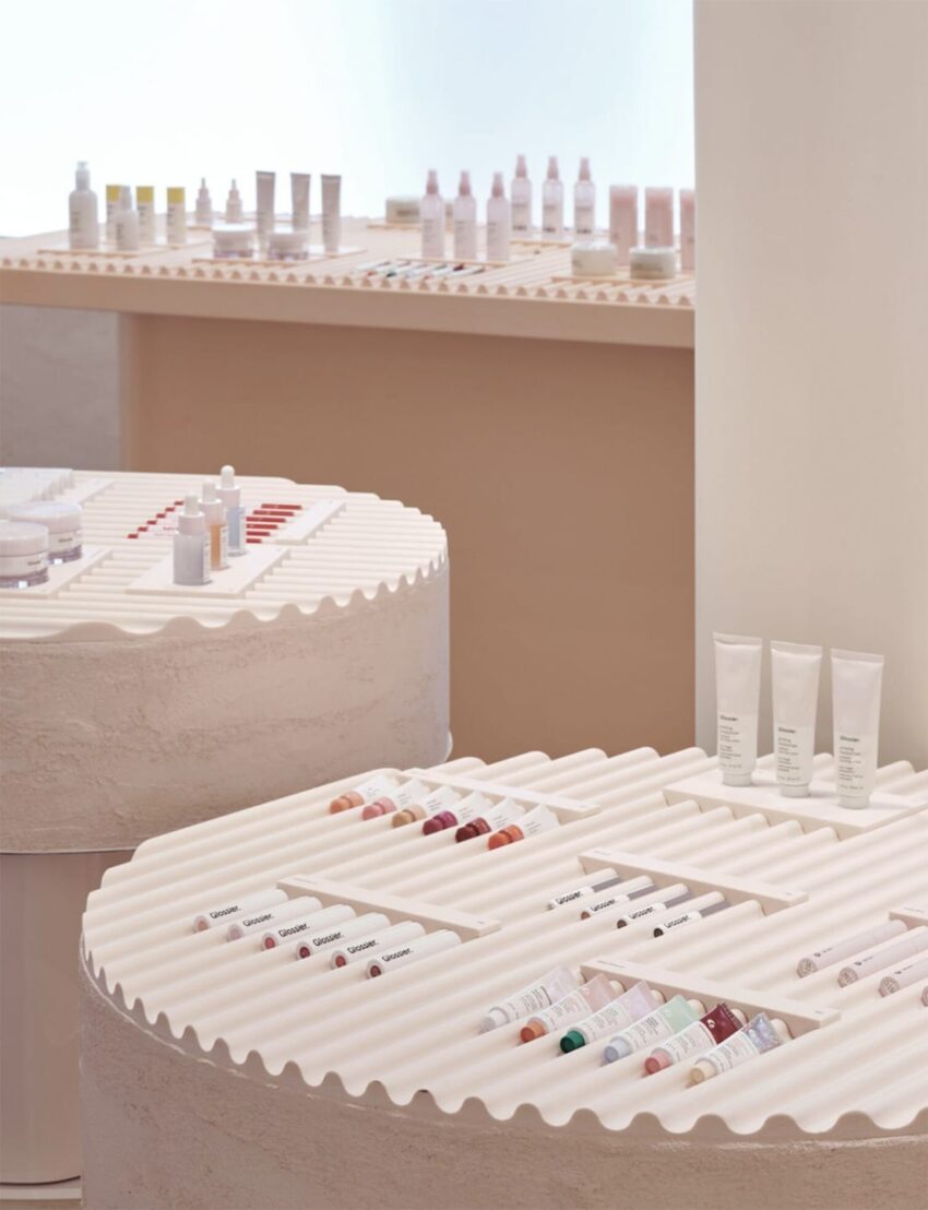 Display of skincare products neatly arranged on textured white circular shelves in a modern retail setting.