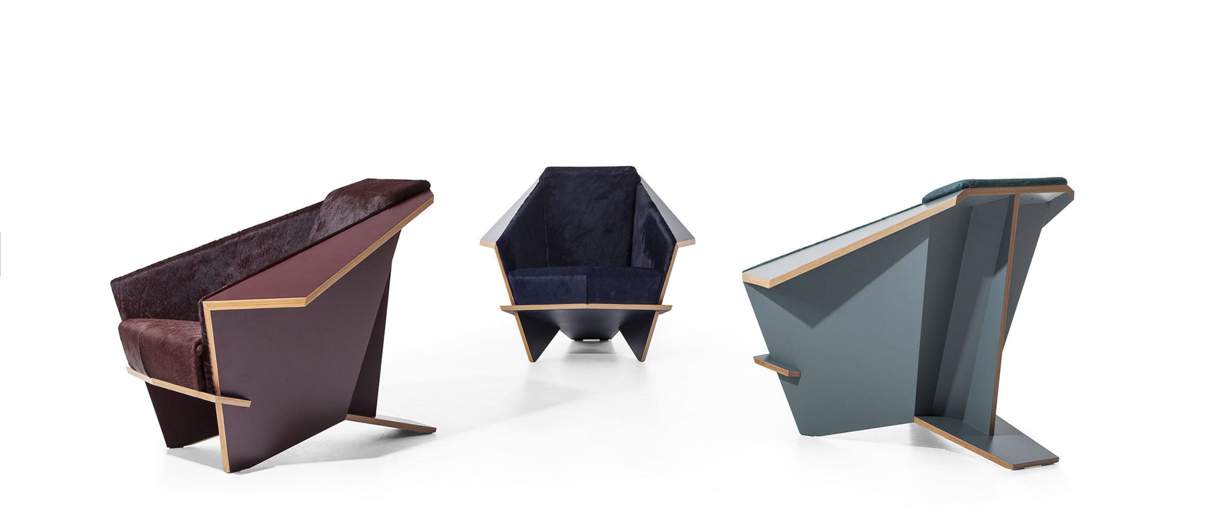 Three modern angular chairs with soft cushions and wooden accents displayed on a white background.