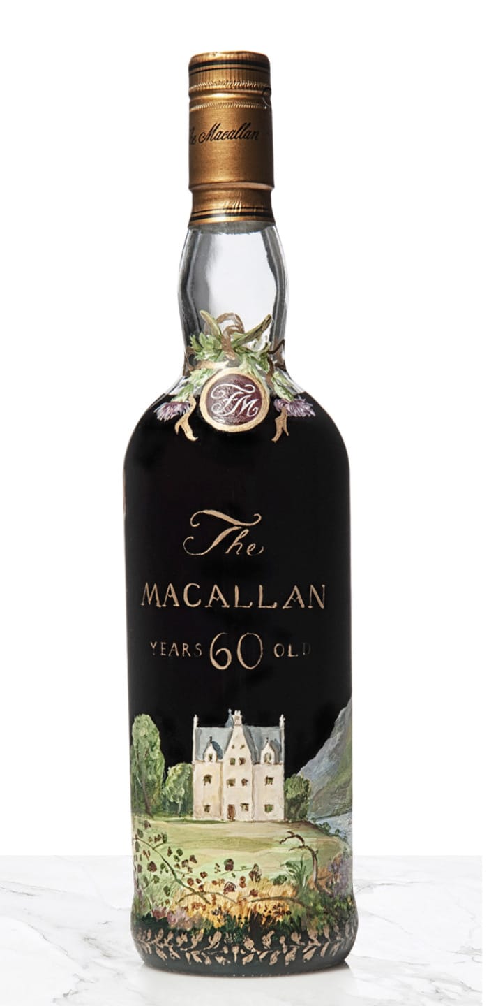 Macallan 60 Year Old whiskey bottle with intricate painted design, displayed on a white surface.