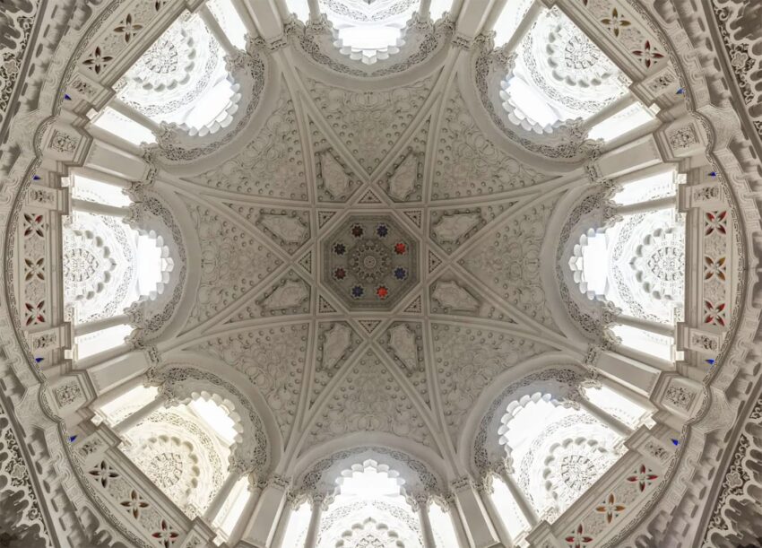 Ornate architectural ceiling with intricate patterns and geometric designs viewed from below, featuring detailed craftsmanship.