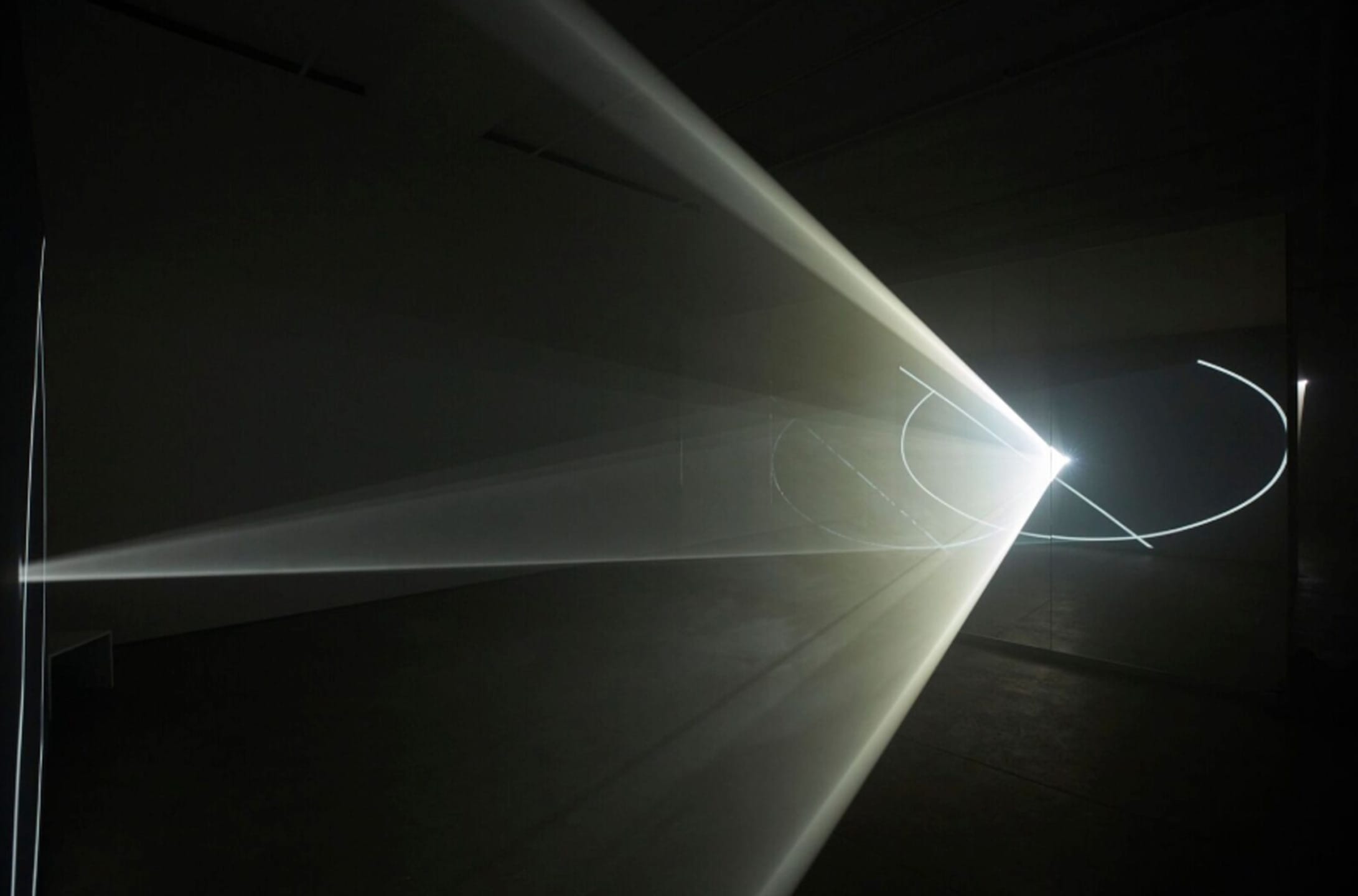 Light beams creating dynamic patterns in a dimly lit room, showcasing a modern art installation with a bright focal point.