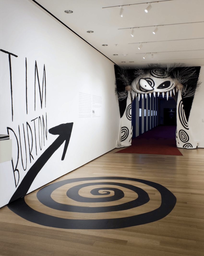 Museum exhibit entrance with a whimsical monster design and "Tim Burton" written on the wall.