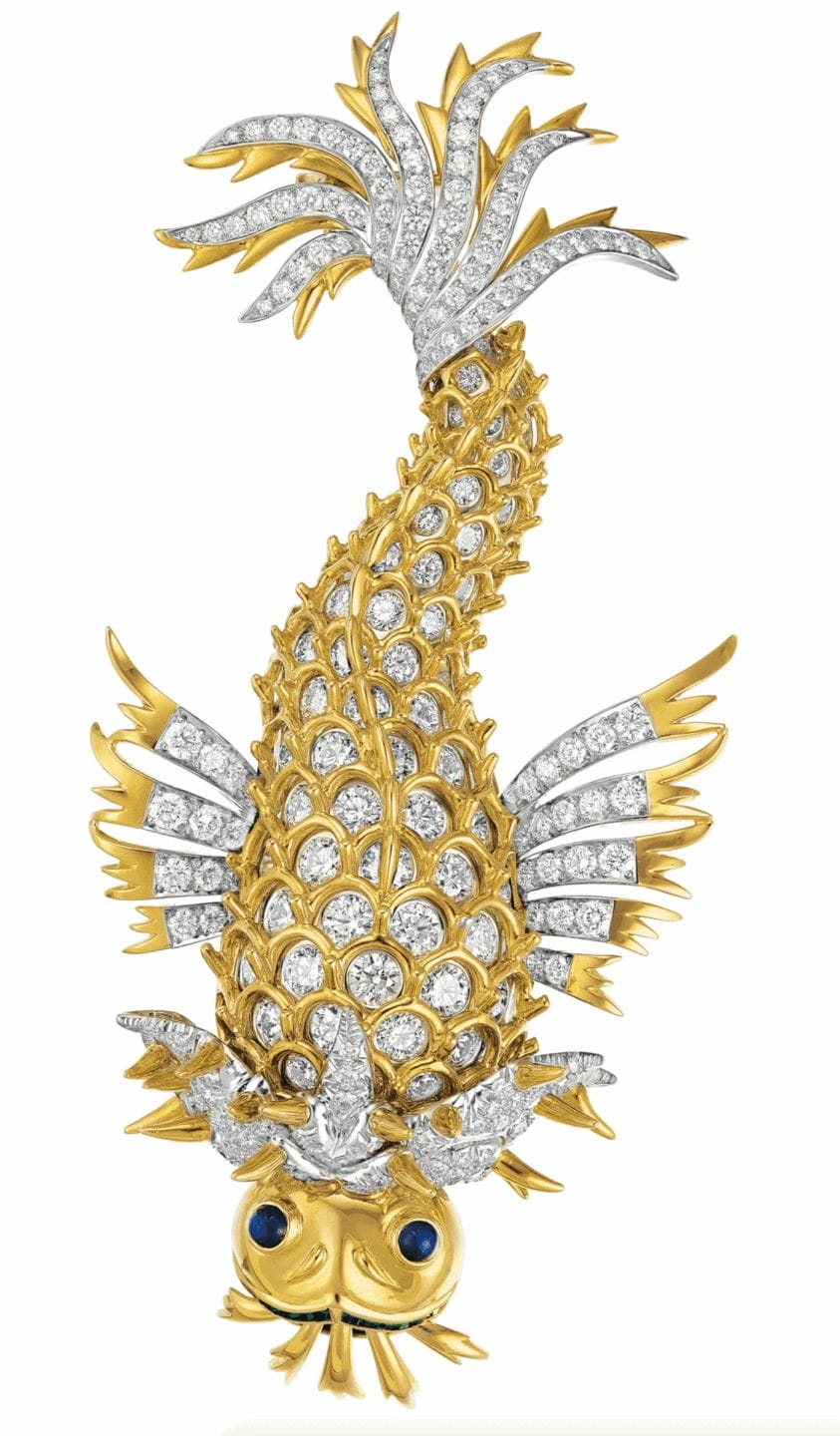 Gold and diamond encrusted fish-shaped brooch with sapphire eyes and intricate details.