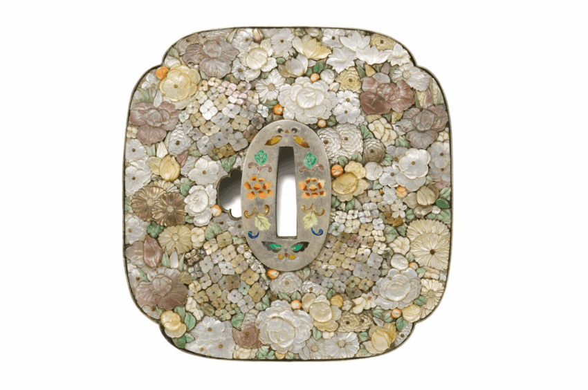 Ornate floral tsuba sword guard with detailed carvings and colorful inlays, featuring various flowers and intricate design.