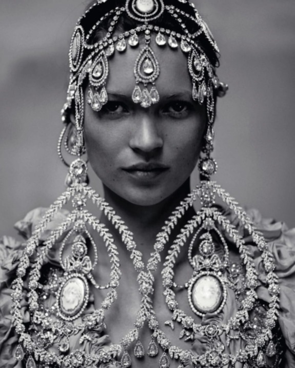 Woman wearing ornate, detailed jewelry and headpiece in an artistic black and white portrait.