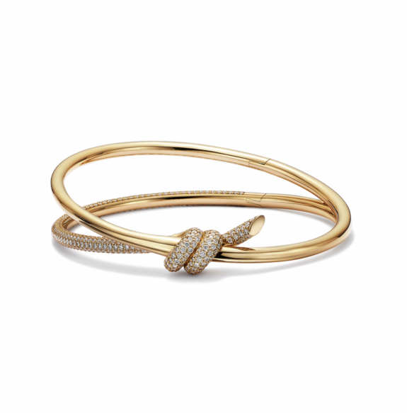 gold bracelet with diamond-encrusted knot design placed on a white background