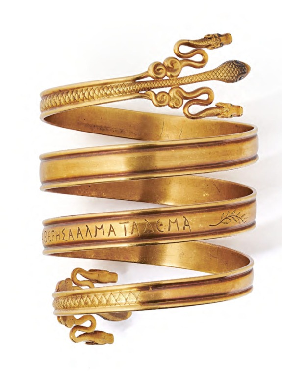 Ancient gold spiral bracelet with engraved lettering and snakehead designs on each end.