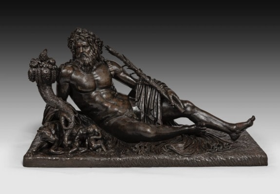 Bronze sculpture of a reclining male figure with a serpent tail and ornate headdress, holding a cornucopia.