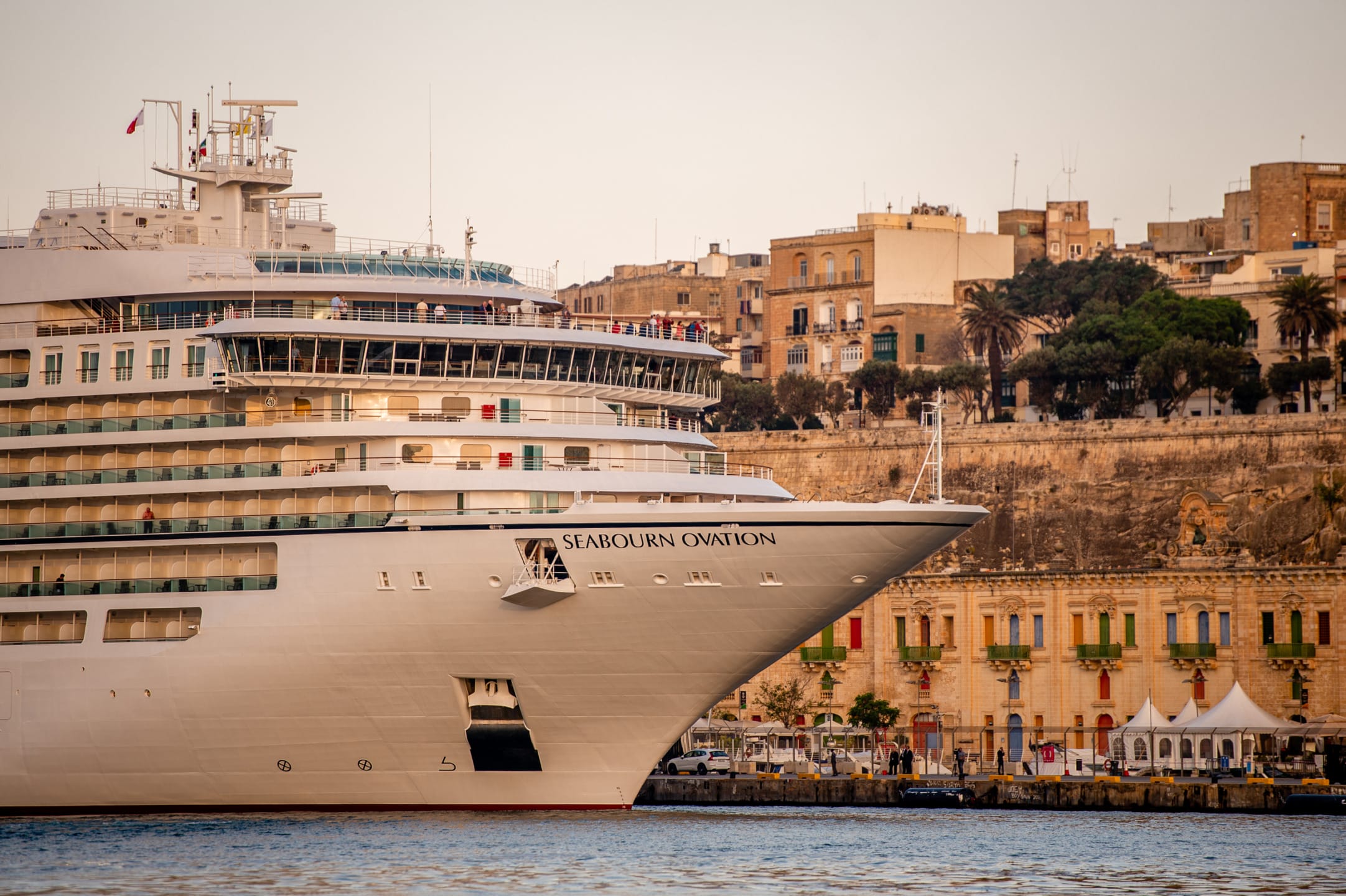 Cruise ship docked near historic waterfront buildings at sunset.