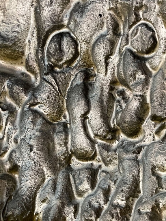 Close-up of textured metallic surface with abstract patterns and varying shades of gray and silver.