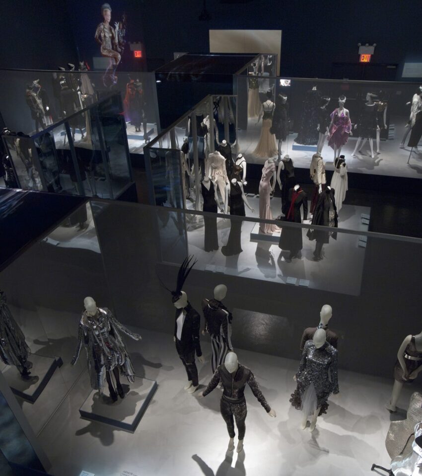 Exhibit showcasing mannequins dressed in various elaborate and artistic fashion designs, viewed from above.