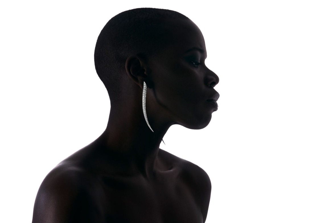 Silhouette of a person with short hair wearing a long, curved earring.