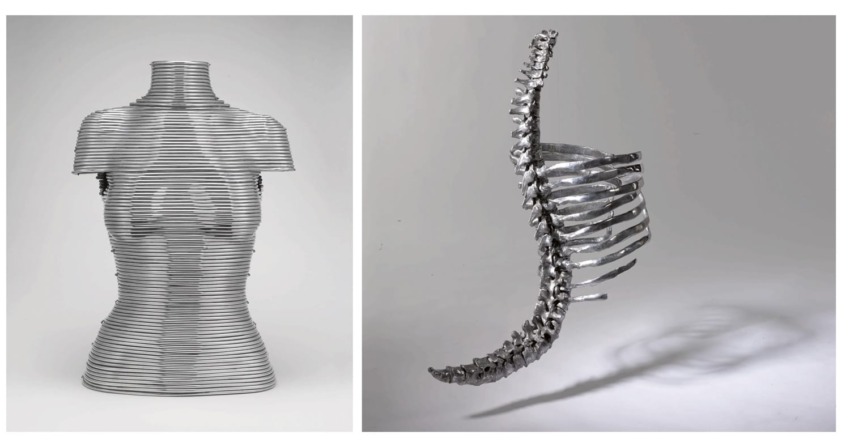 Metal sculptures: a torso made of stacked bands and a curved, rib-like structure suspended, both casting shadows.