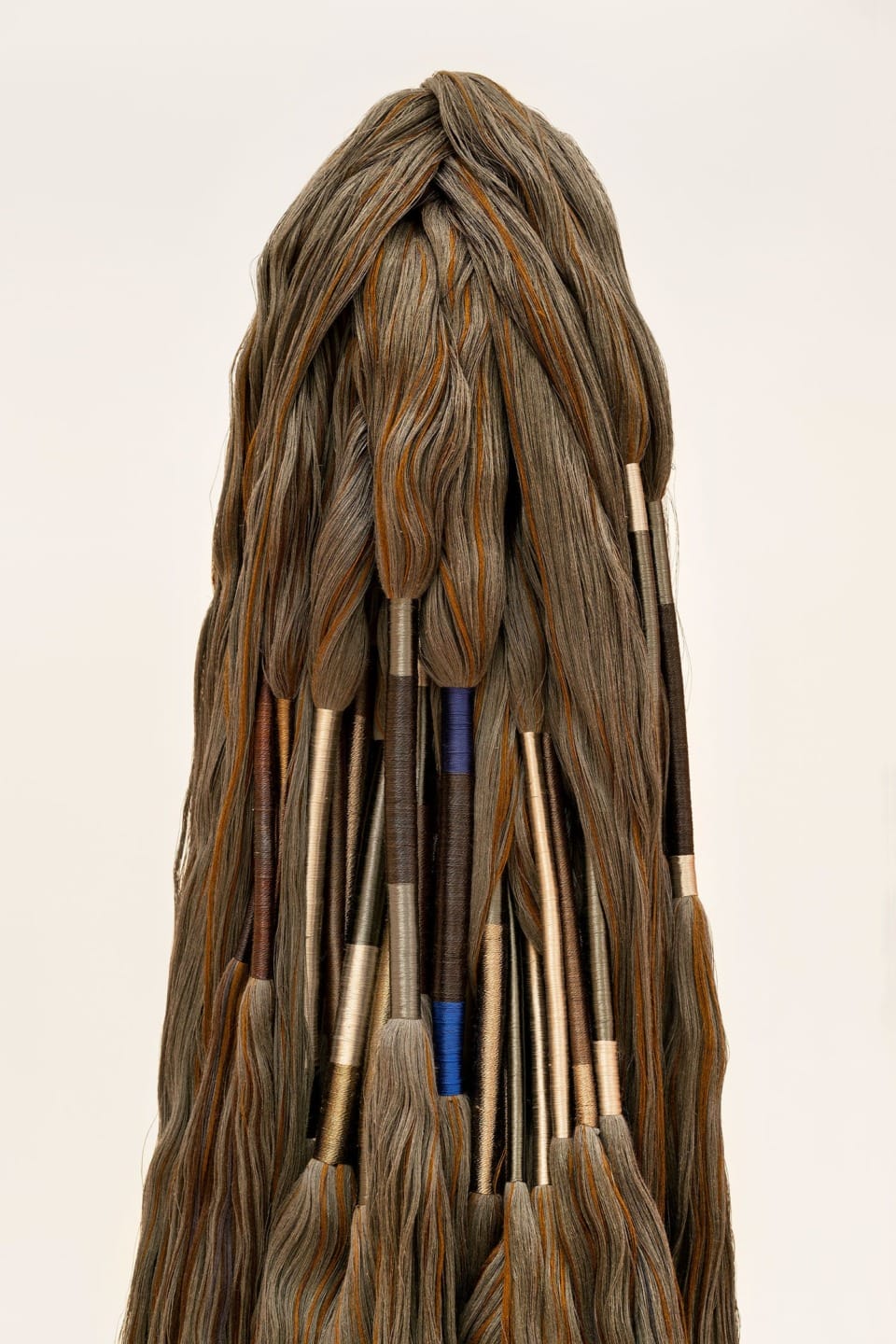 Abstract sculpture resembling brushes with handles, featuring a unique arrangement of textured, hair-like strands.
