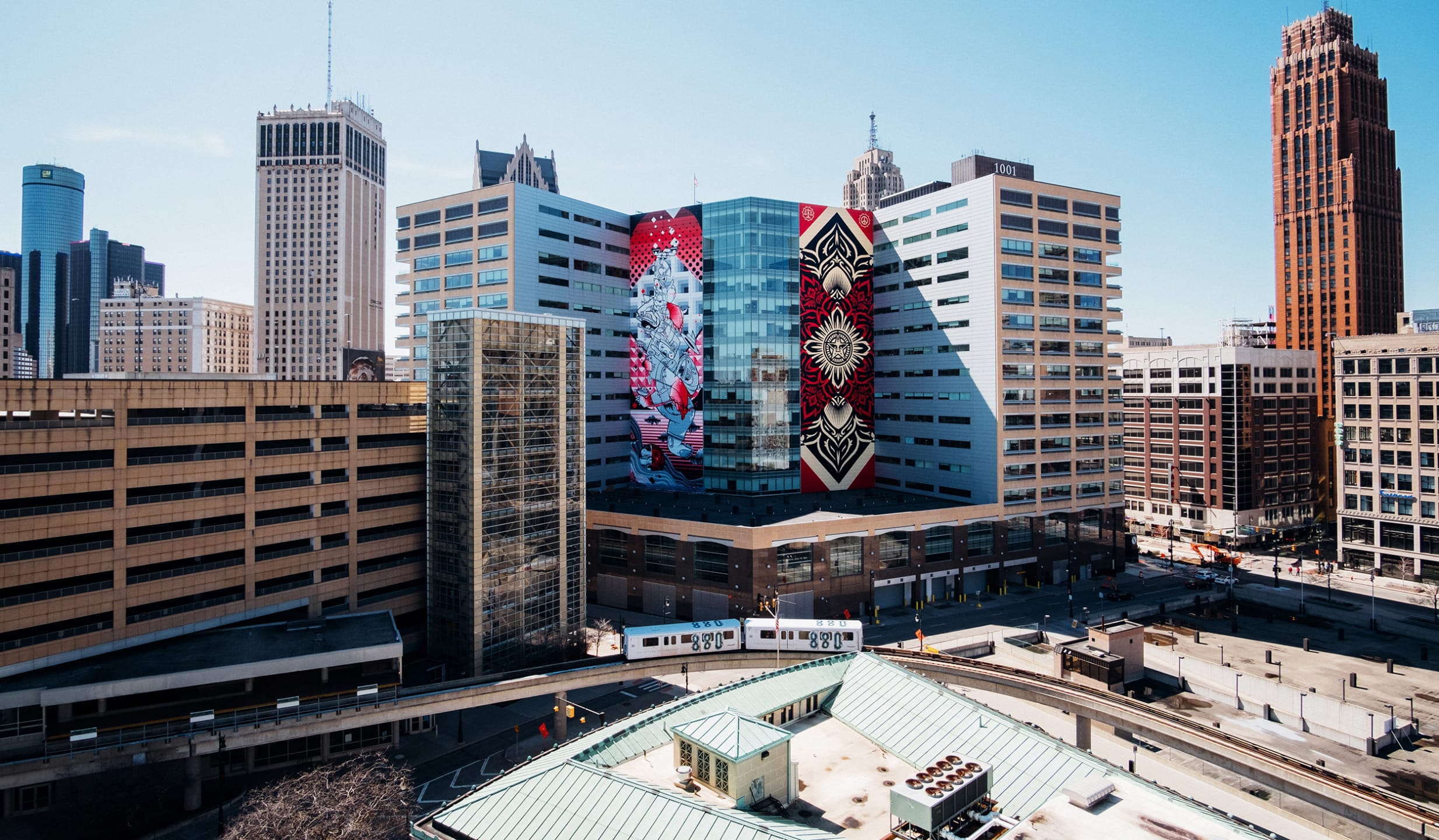 Street art on modern building facade in urban cityscape with train and skyscrapers in the background on a clear day