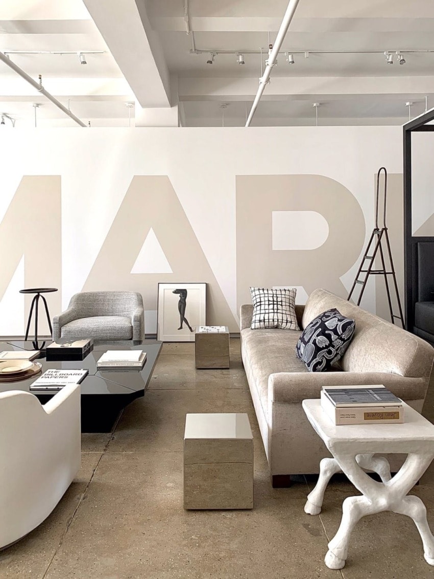 Modern living room with minimalist decor, featuring neutral-colored furniture, art pieces, and geometric accent tables.