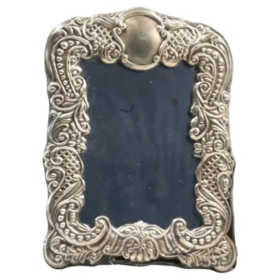 Ornate vintage silver picture frame with intricate decorative patterns on a plain background.