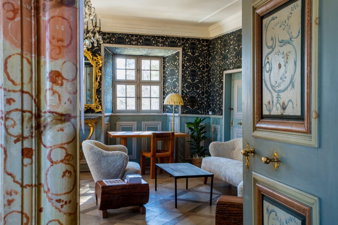 Elegantly decorated vintage room with patterned wallpaper, wooden furniture, and ornate details.