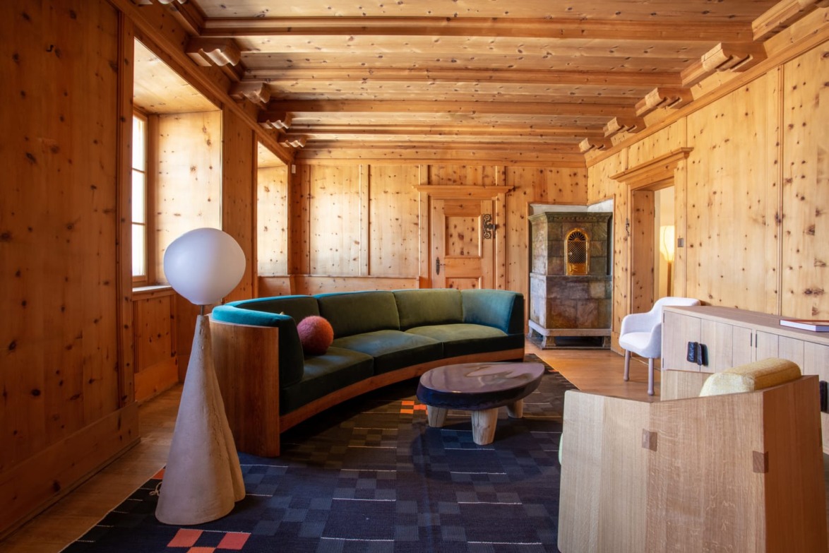 Cozy living room with wooden walls, green sofa, artistic lamps, and modern furniture.