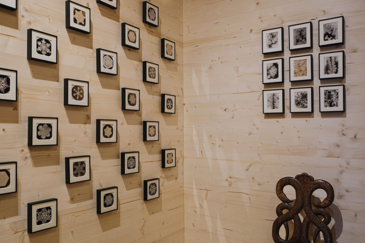 Art gallery wall with framed abstract prints on wooden panels and a wrought iron sculpture in the corner.