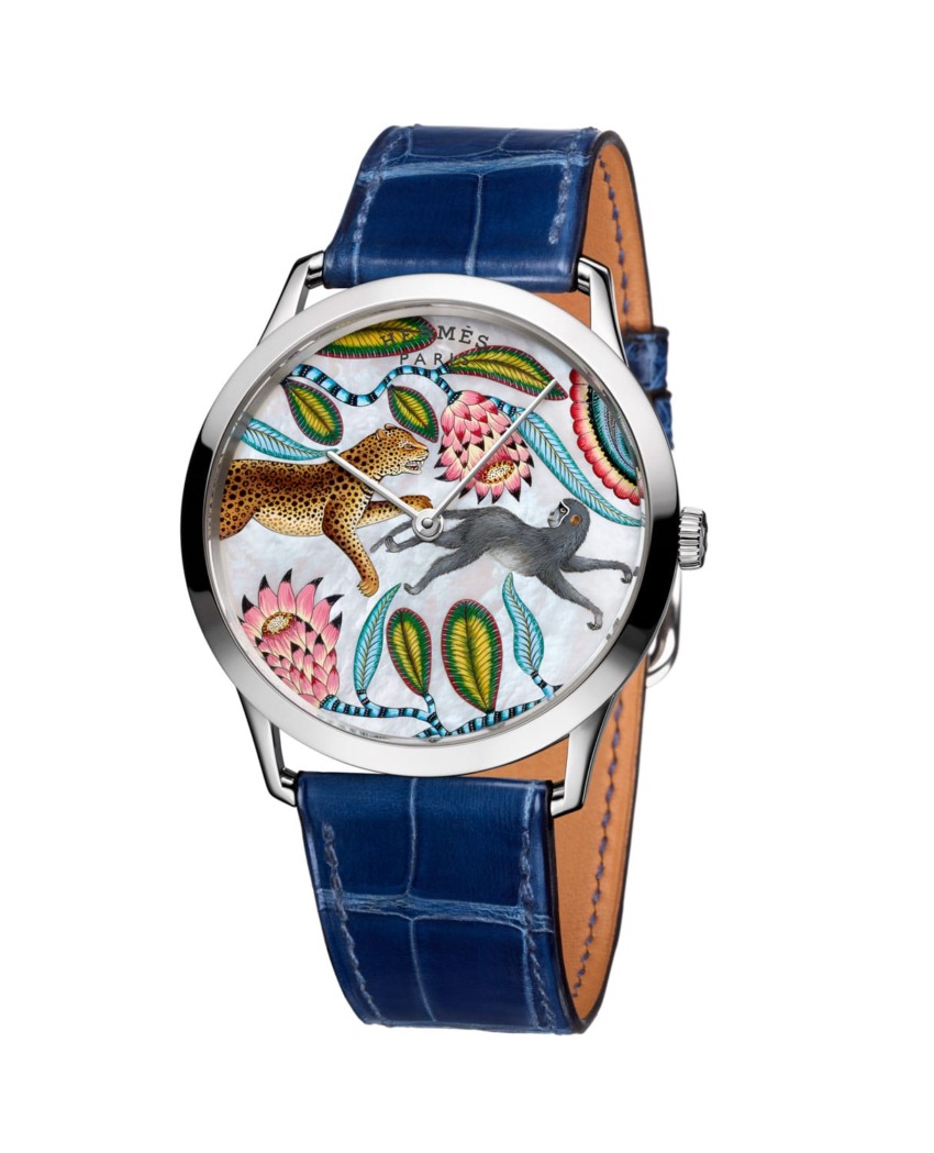 Luxury watch with intricate animal and floral design on dial, blue leather strap, and silver case.