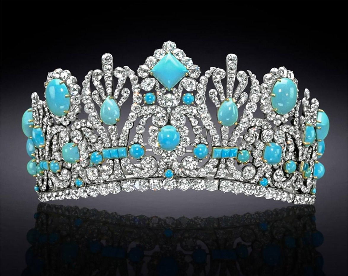 A jeweled tiara adorned with blue gemstones and diamonds on a black reflective surface.