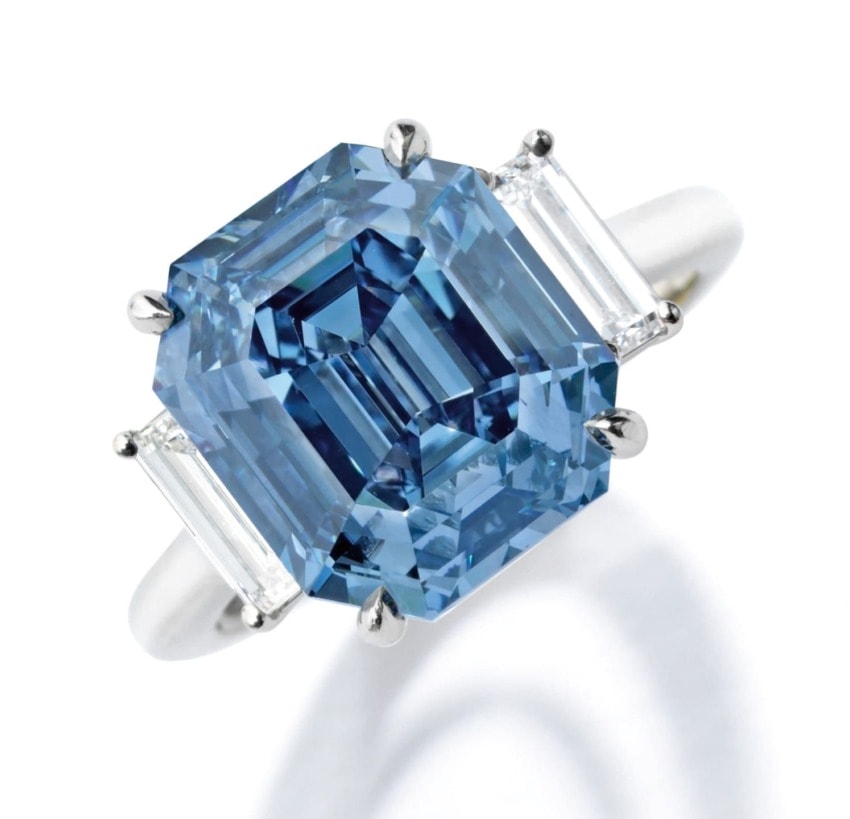 Emerald-cut blue diamond ring with side baguette diamonds on a white gold band