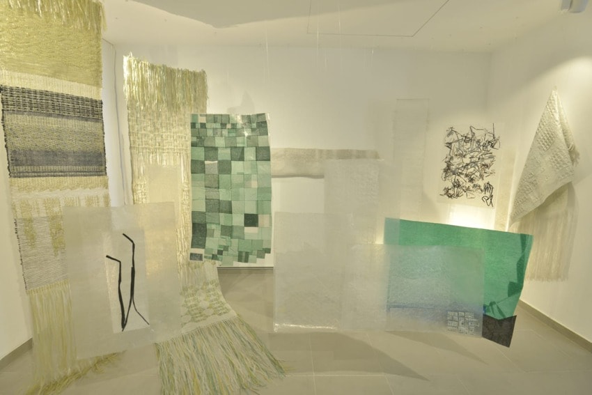 Modern art installation featuring various textured fabrics and geometric patterns displayed in a well-lit gallery space.