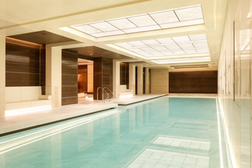Luxurious indoor swimming pool with elegant lighting, modern design, and serene atmosphere, featuring a calm and inviting water surface.