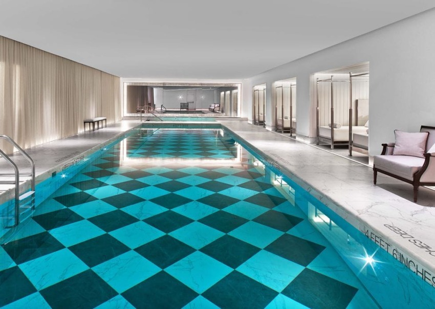 Luxurious indoor swimming pool with a checkered floor pattern, surrounded by elegant lounge chairs in a modern setting.