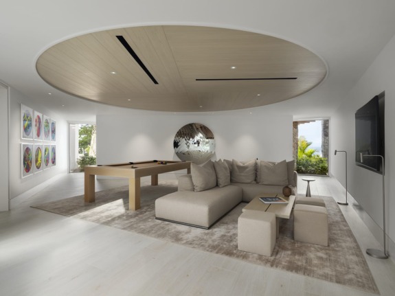 Random Triangle Mirror (2015) by Anish Kapoor animates a lounge area in the new Spice of Life villa at Sugar Beach, a Viceroy Hotel, in St. Lucia. On the wall to the left are works by Damien Hirst and KAWS.