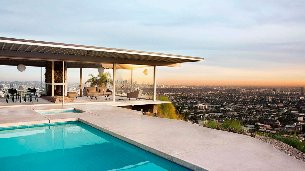 Modern house with pool overlooking cityscape at sunset, featuring outdoor seating and panoramic views of the surrounding area.