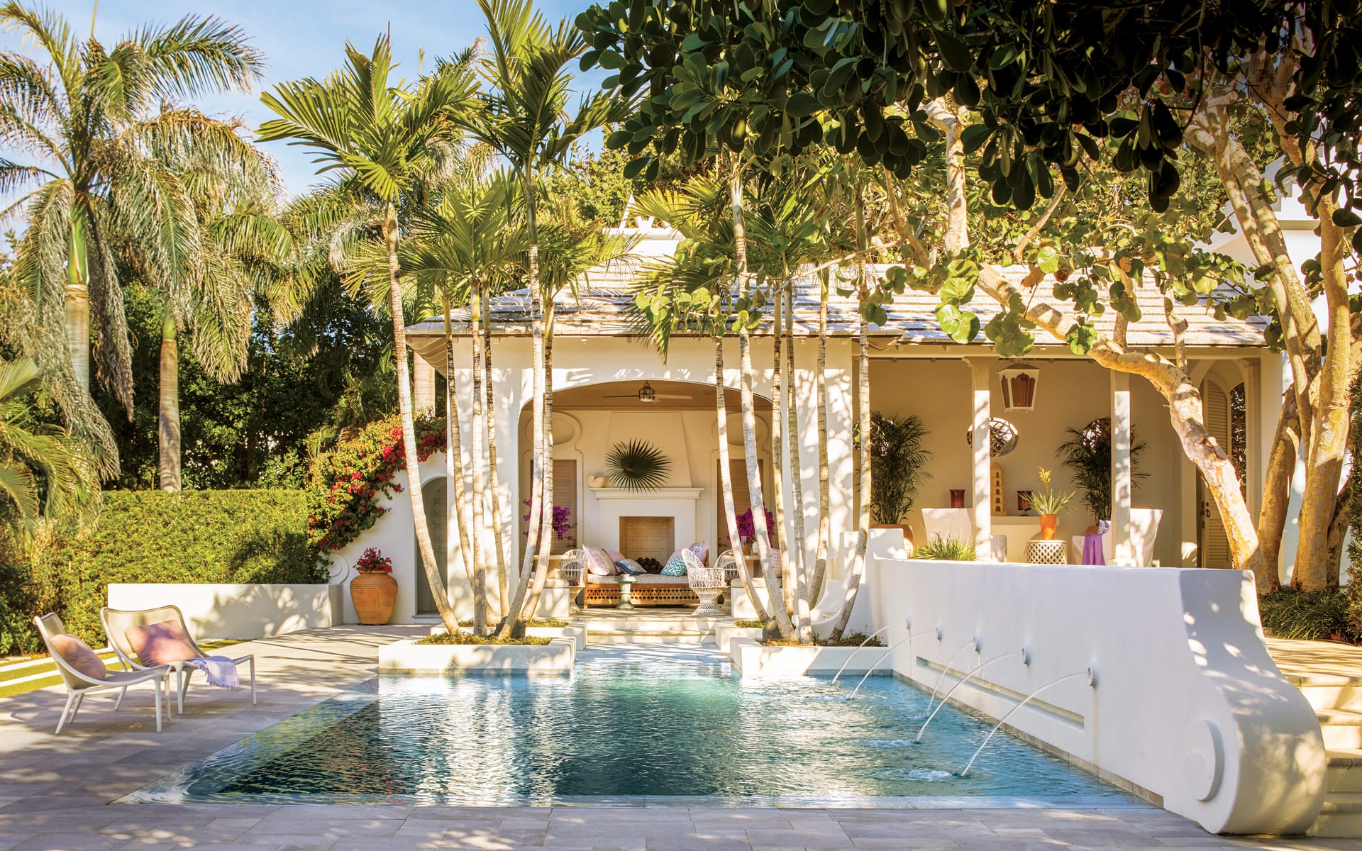 Tropical backyard with a swimming pool, palm trees, and a cozy seating area under a patio canopy.