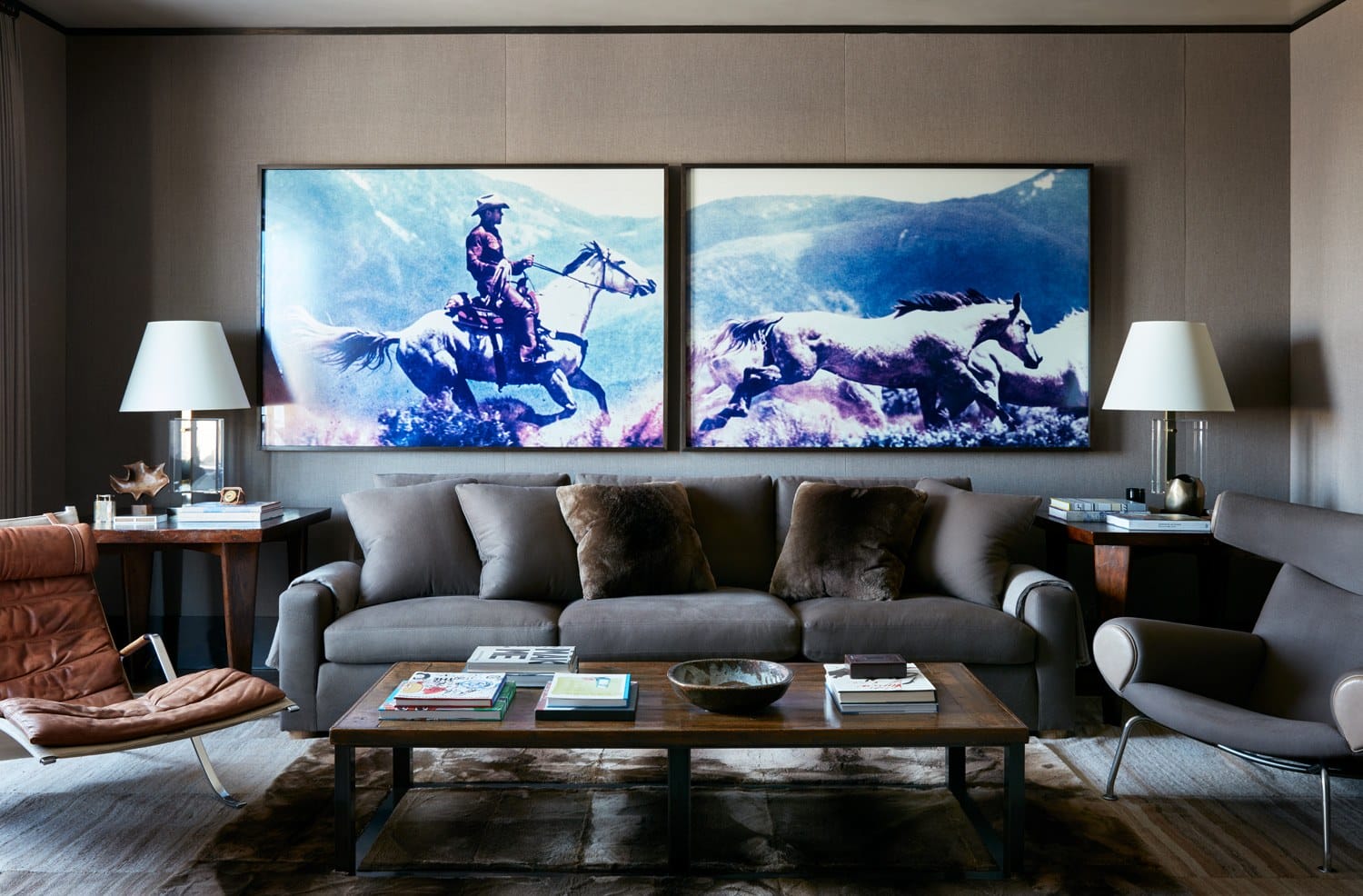 Modern living room with a gray sofa, two horse paintings, wooden coffee table, and stylish chairs.